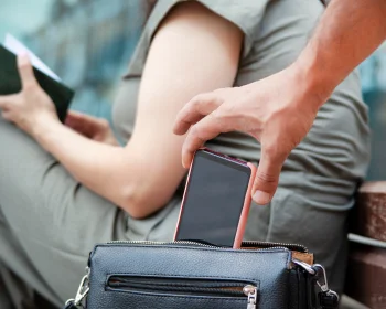 un homme subtilise un téléphone dans un sac à main