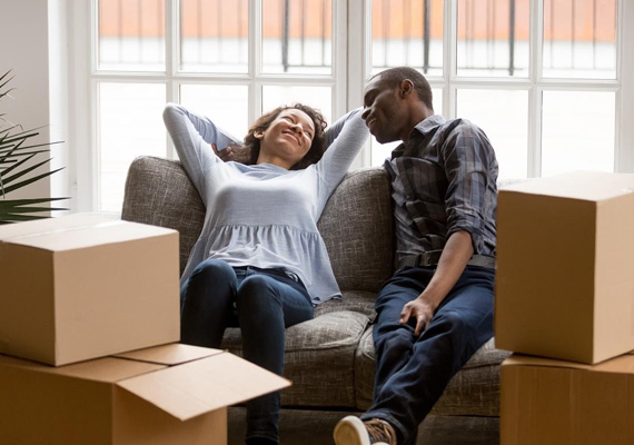 Couple personnes déménage cartons divan gris tissus plante chassis blanc